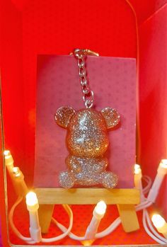 a teddy bear keychain sitting on top of a box with candles around it