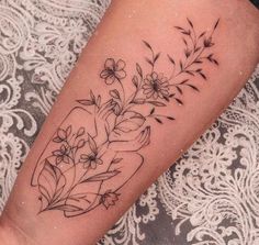 a woman's arm with flowers and leaves on it