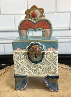 a decorative box sitting on top of a tree stump in front of a tile wall