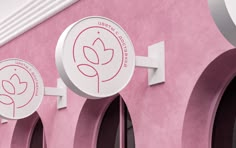 three round signs on the side of a pink building