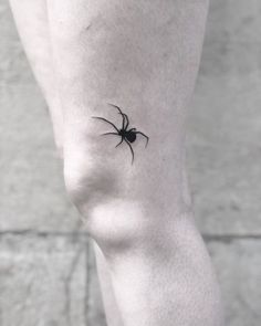 a small black spider tattoo on the leg