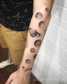 a man with a tattoo on his arm that has the solar system and stars in it