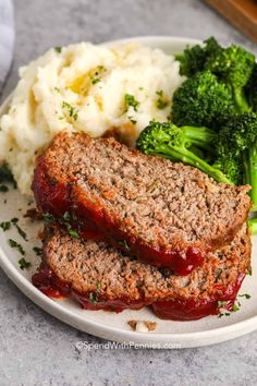 two meatloaf patties on a plate with mashed potatoes and broccoli