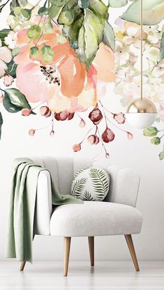 a white chair sitting in front of a wall mural with flowers and leaves on it