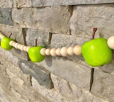 some green apples are hanging on a brick wall