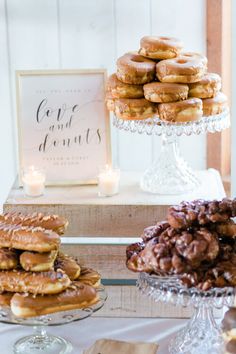 a table topped with lots of donuts next to a cake stand filled with desserts