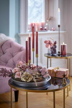 a table topped with candles and flowers on top of a wooden floor next to a pink chair