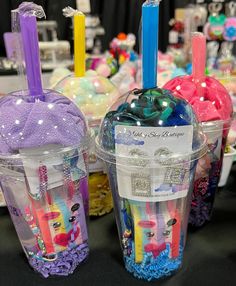 two plastic cups filled with colorful items on top of a black table covered in confetti