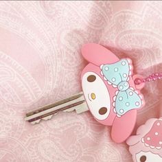 hello kitty keychain with pink bow and polka dots on it, sitting next to a pair of keys