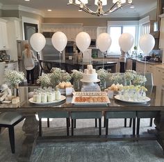 a table with cake, candles and balloons on it in the middle of a kitchen