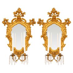 a pair of gilded mirrors with candles on them