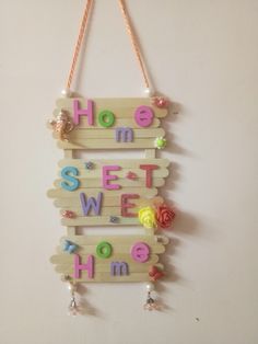 a wooden sign that says home sweet home hanging on a wall with flowers and beads