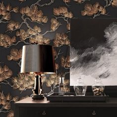 a black and white wallpaper with gold leaves on it, next to a lamp