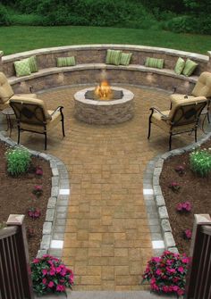 an outdoor fire pit surrounded by chairs and flowers