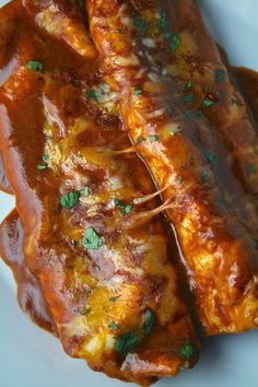 two pieces of meat covered in sauce on a white plate