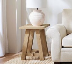 a white vase sitting on top of a wooden table next to a chair in a living room