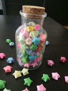 a jar filled with colorful stars on top of a table