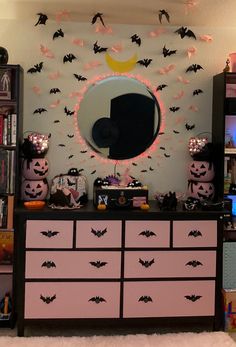 a halloween themed bedroom with bats on the wall and a mirror above it, all decorated in black and pink