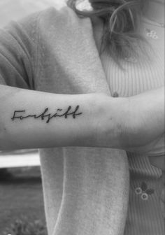 a woman's arm with the word faith written in cursive writing on it