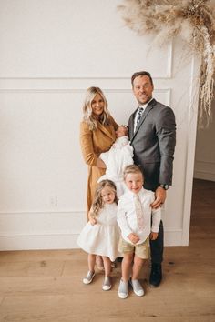 a family posing for a photo in front of a wall with dried grass and flowers