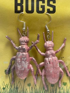 two pink bugs sitting next to each other on top of green grass and yellow background