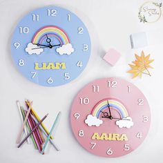 two clocks on the wall, one has a rainbow and the other has letters that spell out iara