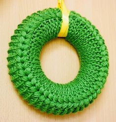 a green crocheted wreath with a yellow ribbon hanging from it's center