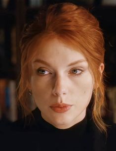 a close up of a person with red hair and blue eyes in a black shirt