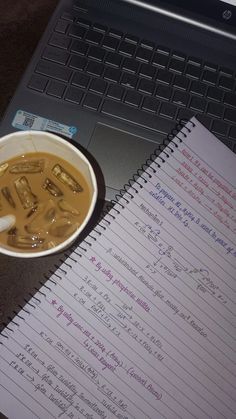 a cup of soup sitting on top of a desk next to a notebook