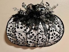 a black and white pumpkin with skulls on it's side hanging from the wall