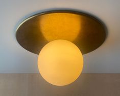 a round light fixture mounted on the ceiling in a room with white walls and beige flooring