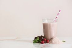 a smoothie with chocolate and raspberries on the side next to some strawberries