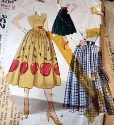 two women's dresses and one is made out of paper with apples on them