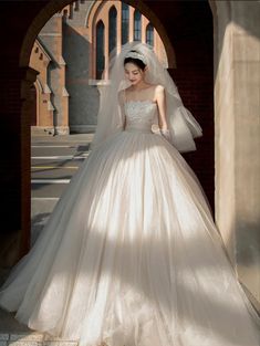 a woman in a wedding dress is posing for the camera with her veil pulled back