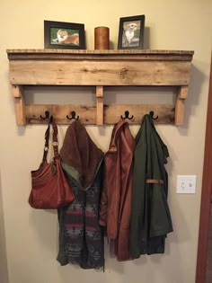 coat rack made out of an old pallet with three coats hanging on it and two purses in front