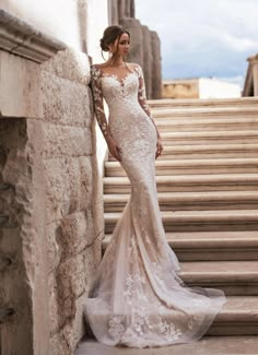 a woman standing on some steps wearing a dress with long sleeves and an open back