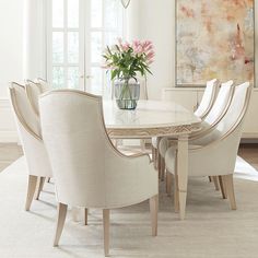 a dining room table with chairs and a vase filled with flowers on top of it