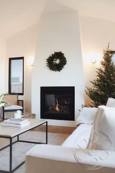 a living room filled with furniture and a fire place next to a christmas wreath on the wall