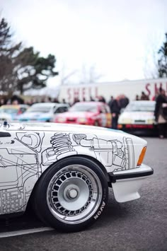 a white and black car parked in a parking lot next to other cars on the street