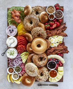 an assortment of doughnuts, fruit and dips on a platter with bacon