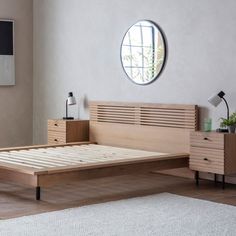 a bed with wooden slats and drawers in a white room next to a round window