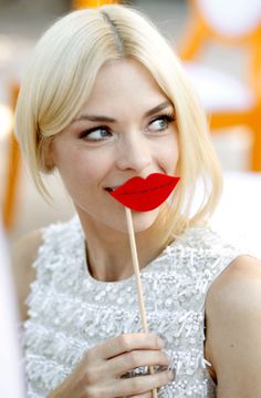 a woman holding a stick with a red lip on it