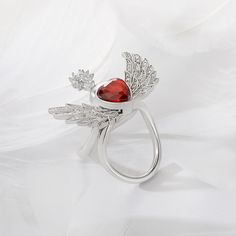 Exquisite and eye-catching, this angel wing ring is destined to be treasured. The angel-inspired design showcases a heart-shaped red stone in the center and a pear-cut white stone (symbolizing the angel’s face) with a half halo around. Her wings feature the rib-textured feathers with small shining white stones completing the style. The timeless piece flutters as you bend your finger, which radiates peace, harmony and charm. The angel's wings will wrap your heart in infinite security. Carat Weigh Elegant Winged Rings As Gifts, Elegant Winged Rings For Gifts, Flying Angel, Wing Ring, Angel Wing Ring, Angel S, White Stones, Red Stone, White Stone