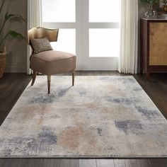 a living room area with a chair, window and rug on the hardwood flooring