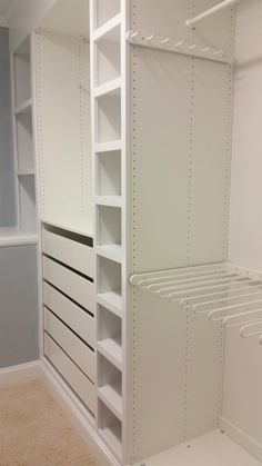 an empty walk in closet with white shelving