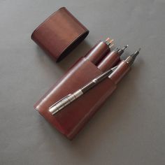 three pens in a leather case on a table