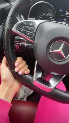 a woman driving a car with pink and black interior