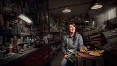 a woman sitting in a room with lots of clutter