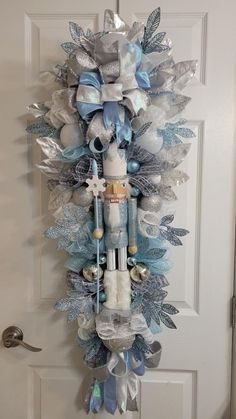 a christmas wreath hanging on the front door with blue and silver decorations, snowflakes and angel wings