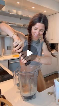 a woman is making something in a blender